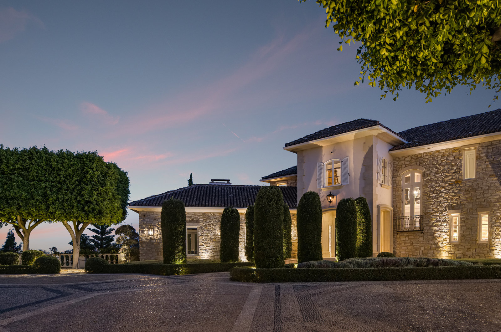 Illuminated motor court and stone exterior at twilight